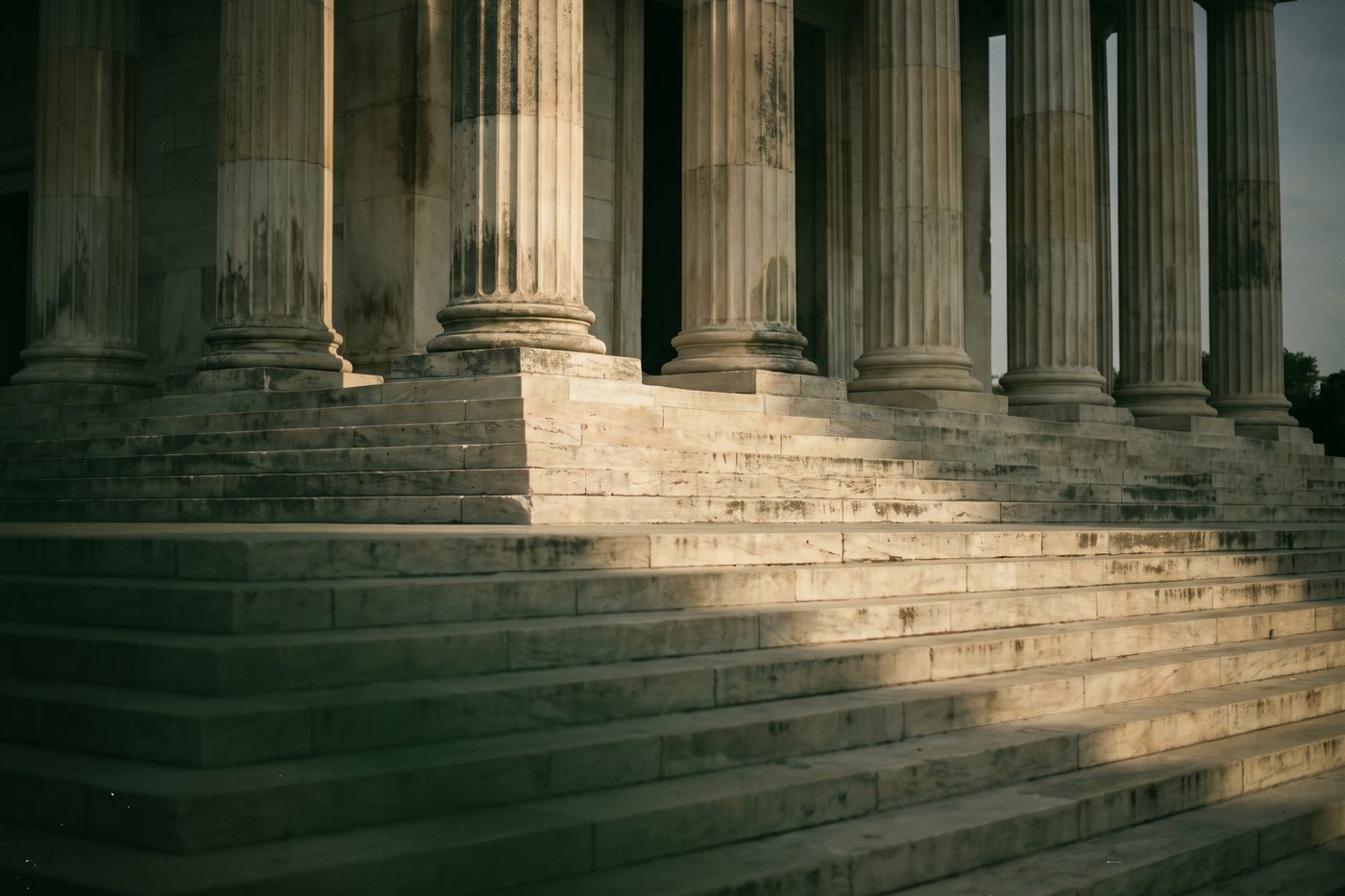 Wide pale limestone steps rising toward tall stone columns in morning light, empty